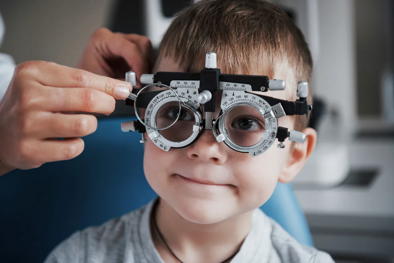 Optometrist performing a detailed eye examination on a young patient using a phoropter